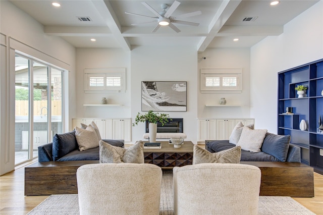 living area featuring light wood finished floors, coffered ceiling, and visible vents