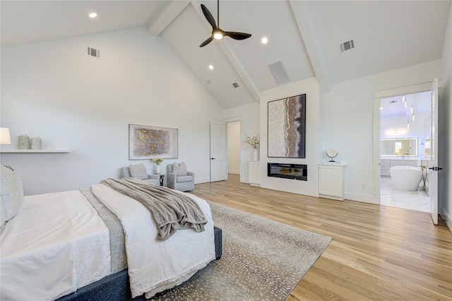 bedroom with high vaulted ceiling, visible vents, wood finished floors, and a glass covered fireplace