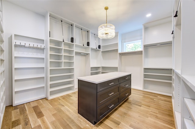 walk in closet featuring light wood-type flooring and a notable chandelier