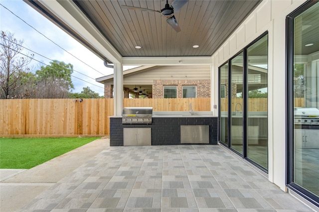 view of patio / terrace with area for grilling, ceiling fan, fence, exterior kitchen, and a sink