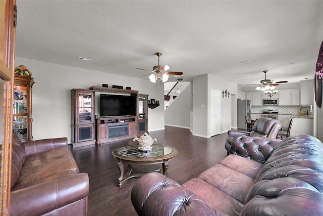 living room with dark wood-style floors, a textured ceiling, baseboards, and a ceiling fan