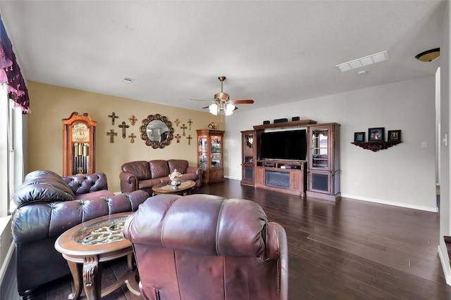 living room featuring baseboards, dark wood-type flooring, visible vents, and a ceiling fan