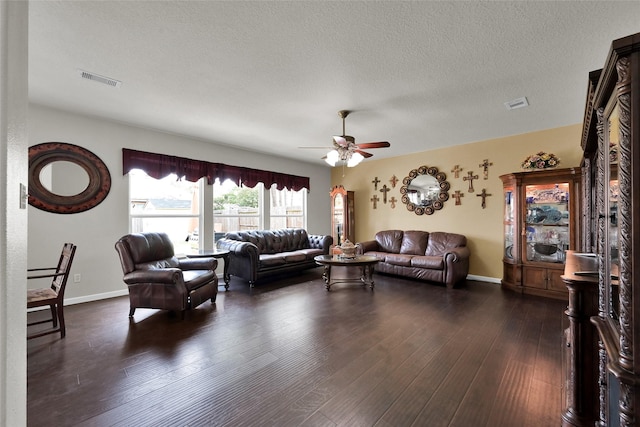 living room featuring dark wood-style floors, visible vents, a ceiling fan, a textured ceiling, and baseboards