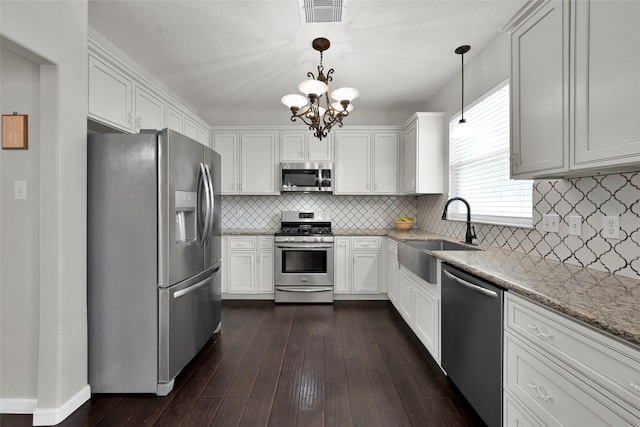 kitchen featuring pendant lighting, visible vents, appliances with stainless steel finishes, white cabinetry, and a sink