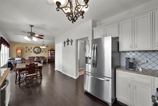 kitchen with stone countertops, dark wood finished floors, open floor plan, tasteful backsplash, and stainless steel fridge