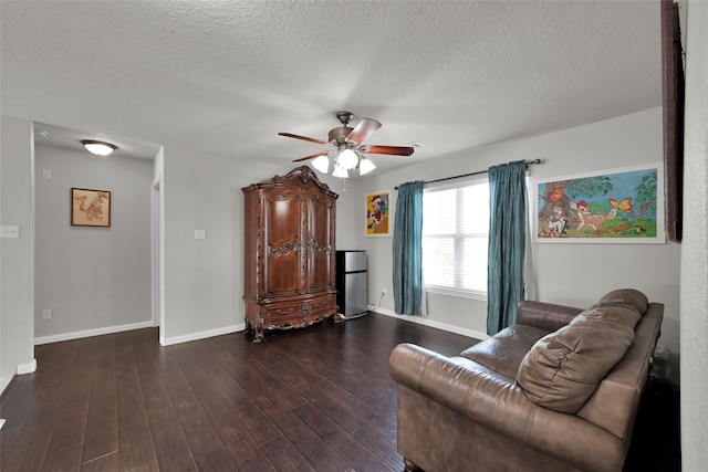 sitting room featuring baseboards, a textured ceiling, a ceiling fan, and dark wood-type flooring