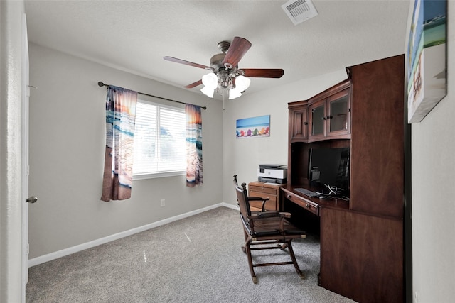 office space featuring a textured ceiling, carpet floors, a ceiling fan, visible vents, and baseboards