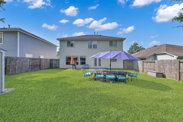 back of house with a fenced backyard and a lawn