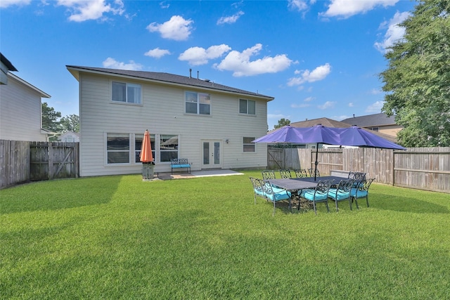 rear view of house with a fenced backyard, a patio, a lawn, and french doors