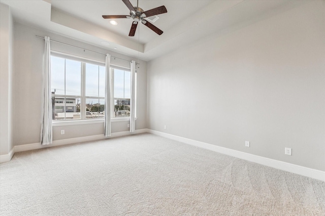 carpeted empty room featuring ceiling fan, baseboards, a raised ceiling, and recessed lighting