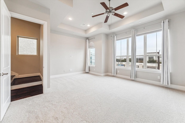 carpeted empty room with recessed lighting, a raised ceiling, a ceiling fan, and baseboards