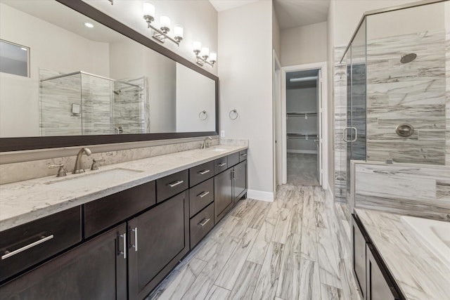 full bath with a sink, a spacious closet, a shower stall, and double vanity