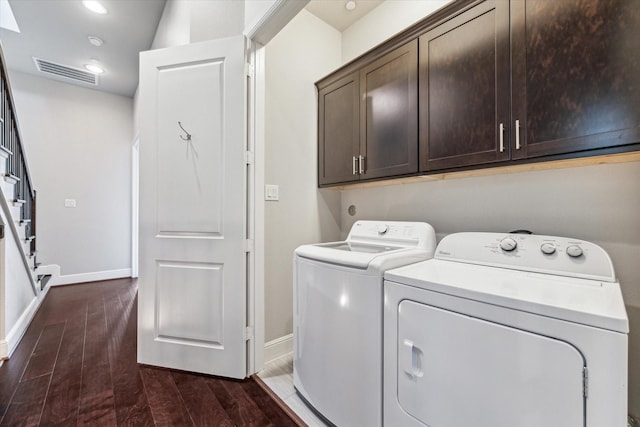 washroom featuring visible vents, baseboards, washer and dryer, cabinet space, and dark wood finished floors