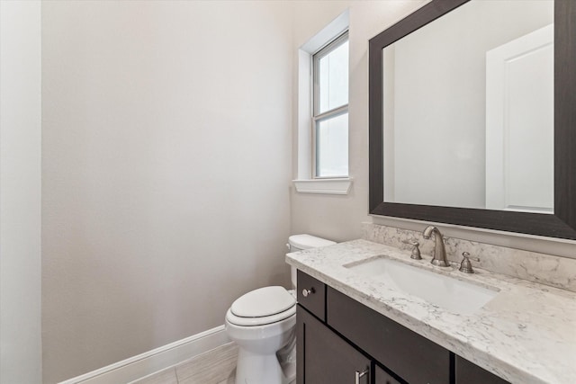 bathroom featuring toilet, vanity, and baseboards