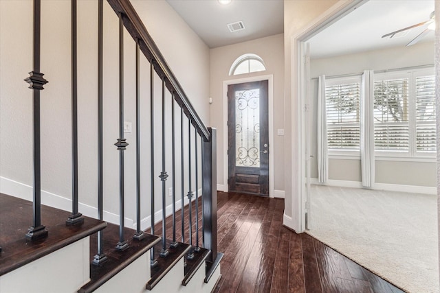 entrance foyer with dark wood-style flooring, visible vents, stairway, a ceiling fan, and baseboards