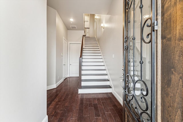 foyer with stairway, dark wood-style flooring, visible vents, and baseboards