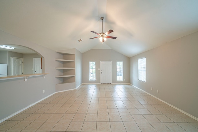 empty room with built in features, arched walkways, light tile patterned floors, visible vents, and baseboards