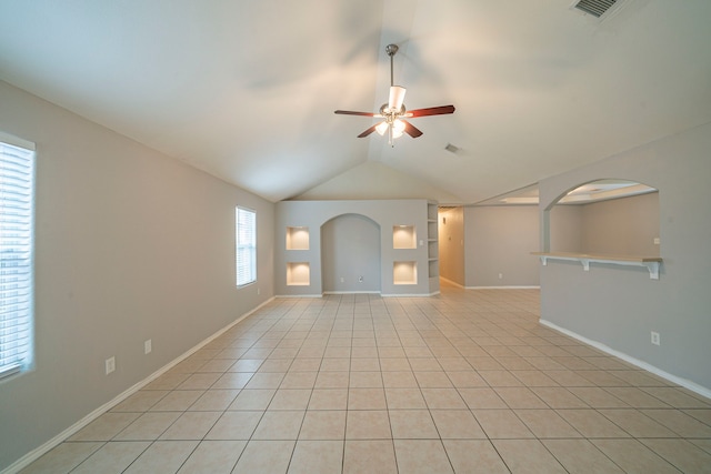 empty room featuring a wealth of natural light, ceiling fan, lofted ceiling, and light tile patterned floors