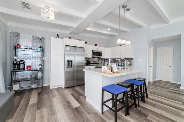 kitchen with a breakfast bar area, stainless steel appliances, a peninsula, white cabinets, and light countertops