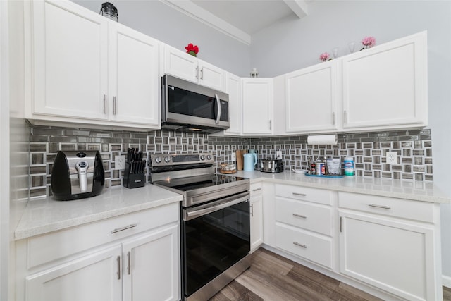 kitchen with dark wood-style flooring, stainless steel appliances, backsplash, white cabinetry, and light stone countertops