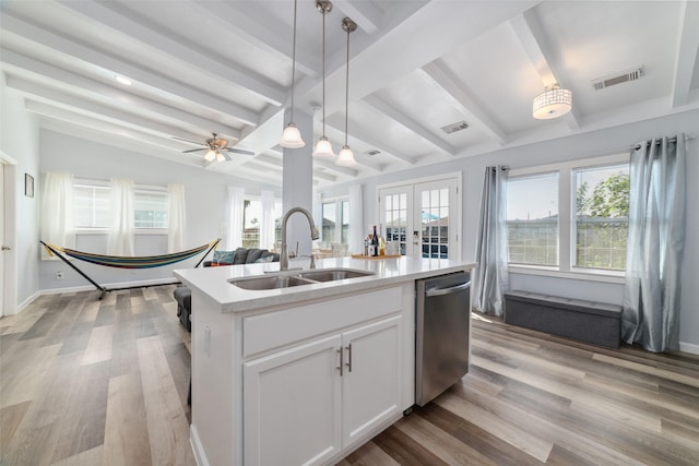 kitchen featuring a sink, visible vents, white cabinets, stainless steel dishwasher, and a center island with sink