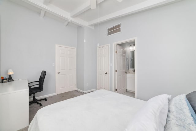 bedroom featuring visible vents, baseboards, beamed ceiling, dark carpet, and ensuite bath