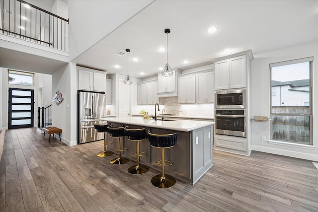 9410 Knollwood Ln, Missouri City, TX 77459 - kitchen with an island with sink, appliances with stainless steel finishes, hanging light fixtures, light countertops, and white cabinetry