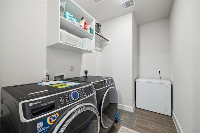9410 Knollwood Ln, Missouri City, TX 77459 - clothes washing area with dark wood-style flooring, visible vents, separate washer and dryer, laundry area, and baseboards