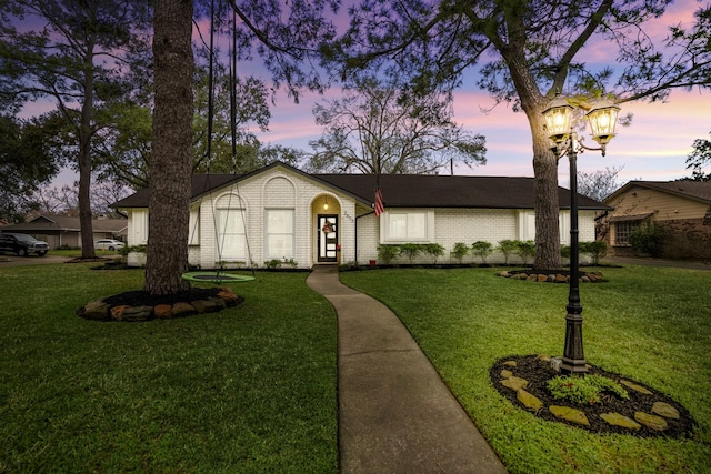 view of front of property featuring brick siding and a yard