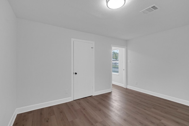 empty room featuring baseboards, visible vents, and dark wood-type flooring