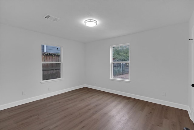 spare room featuring wood finished floors, visible vents, and baseboards