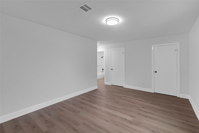 unfurnished room featuring wood finished floors, visible vents, and baseboards