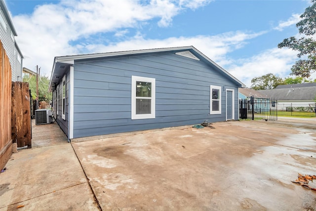 view of side of home with central air condition unit, fence, and a patio