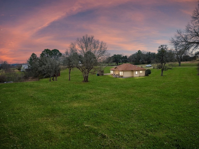 yard at dusk featuring an attached garage