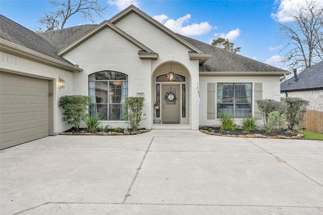 view of front of property with an attached garage, brick siding, a shingled roof, and fence