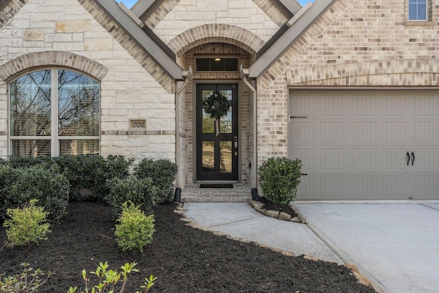 doorway to property featuring concrete driveway, brick siding, an attached garage, and stone siding