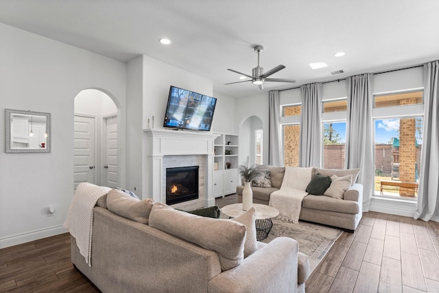 living area featuring arched walkways, dark wood finished floors, and visible vents