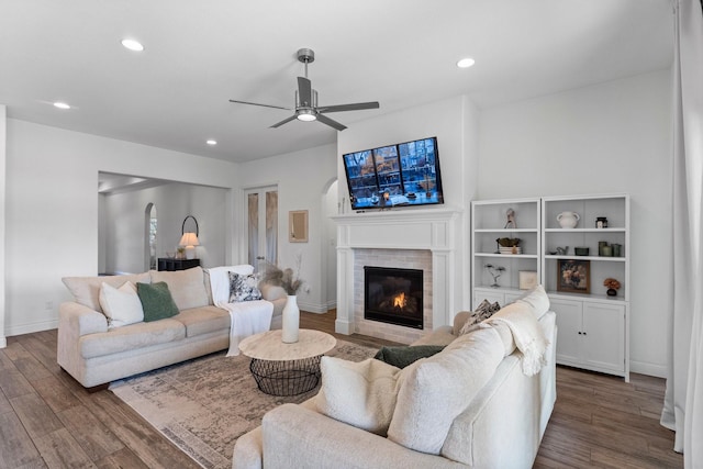 living area with baseboards, dark wood-type flooring, a brick fireplace, and recessed lighting