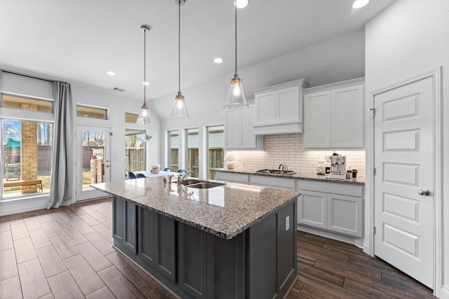 kitchen with light stone counters, white cabinets, and a sink