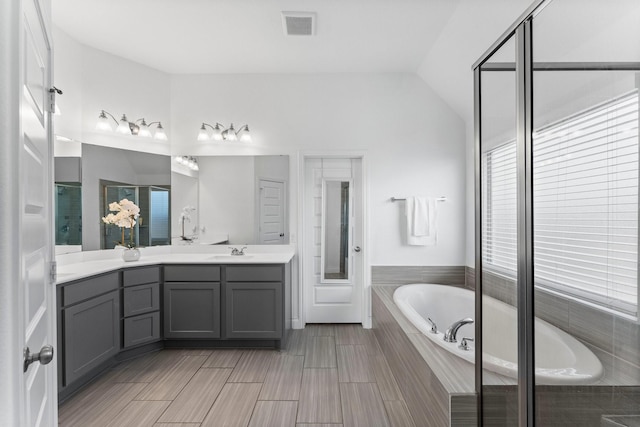 bathroom featuring a shower with shower door, visible vents, vanity, vaulted ceiling, and a bath