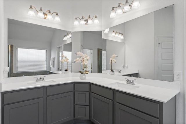 bathroom with vaulted ceiling, a sink, and double vanity