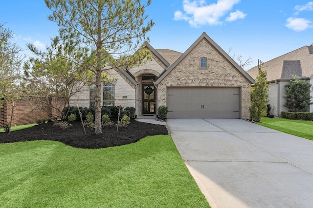 french country style house with brick siding, concrete driveway, an attached garage, a front yard, and stone siding