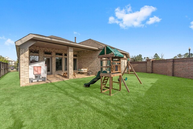 back of house featuring a playground, brick siding, a lawn, a patio area, and a fenced backyard