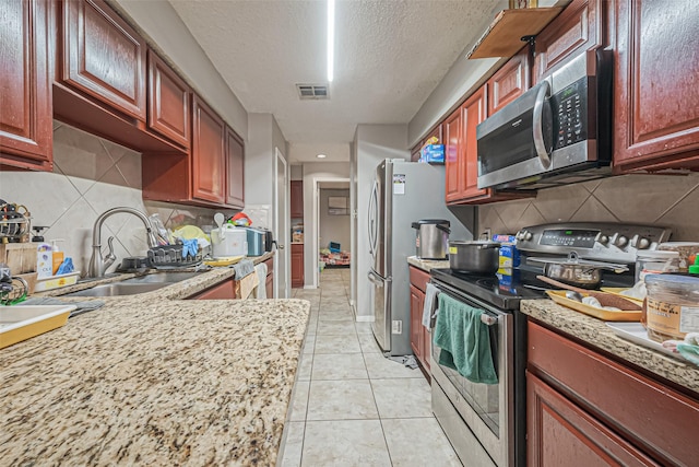 9319 Belle Park Dr, Houston, TX 77099 - kitchen featuring visible vents, appliances with stainless steel finishes, light stone counters, a sink, and light tile patterned flooring