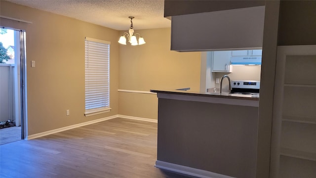 kitchen featuring hanging light fixtures, stainless steel electric stove, a textured ceiling, under cabinet range hood, and white cabinetry