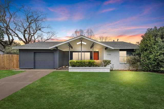 view of front of property featuring an attached garage, driveway, fence, and a front yard