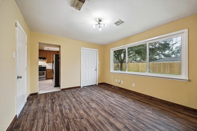 unfurnished bedroom with light wood finished floors, baseboards, visible vents, and freestanding refrigerator