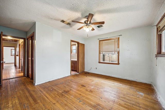 spare room featuring ceiling fan, a textured ceiling, baseboards, and wood finished floors