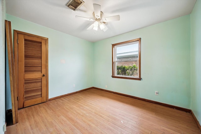 empty room with light wood-type flooring, ceiling fan, visible vents, and baseboards