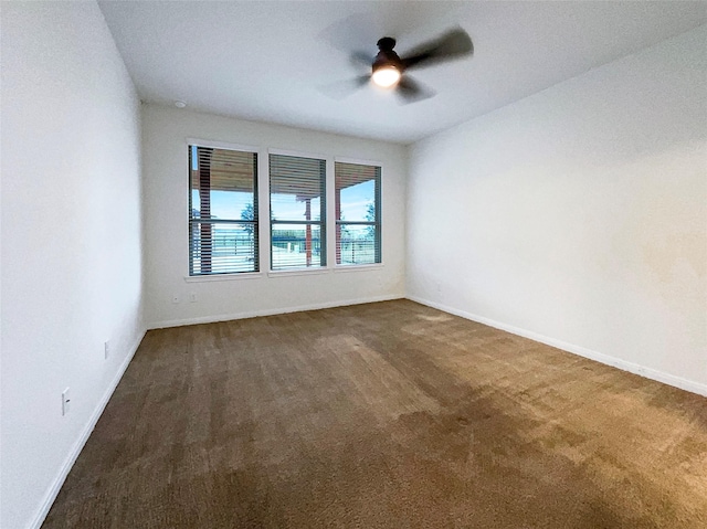 unfurnished room featuring ceiling fan, baseboards, and dark colored carpet